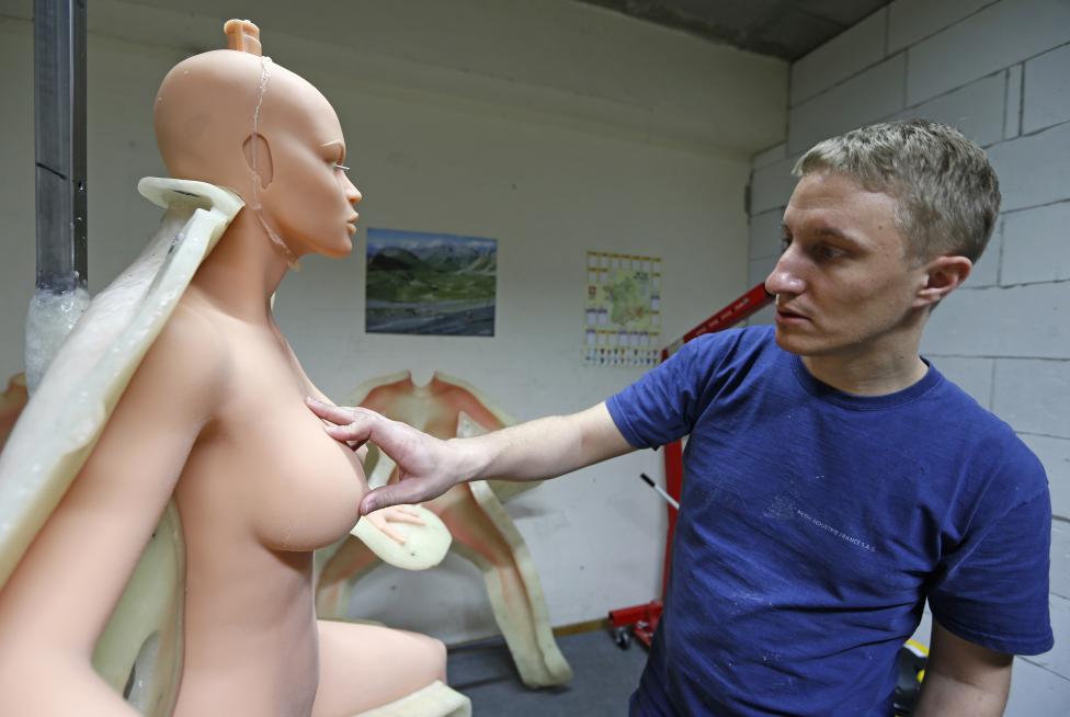 Eric, an employee at the Dreamdoll company, inspects a silicone dream doll as he removes it from a mold at their workshop in Duppigheim near Strasbourg
